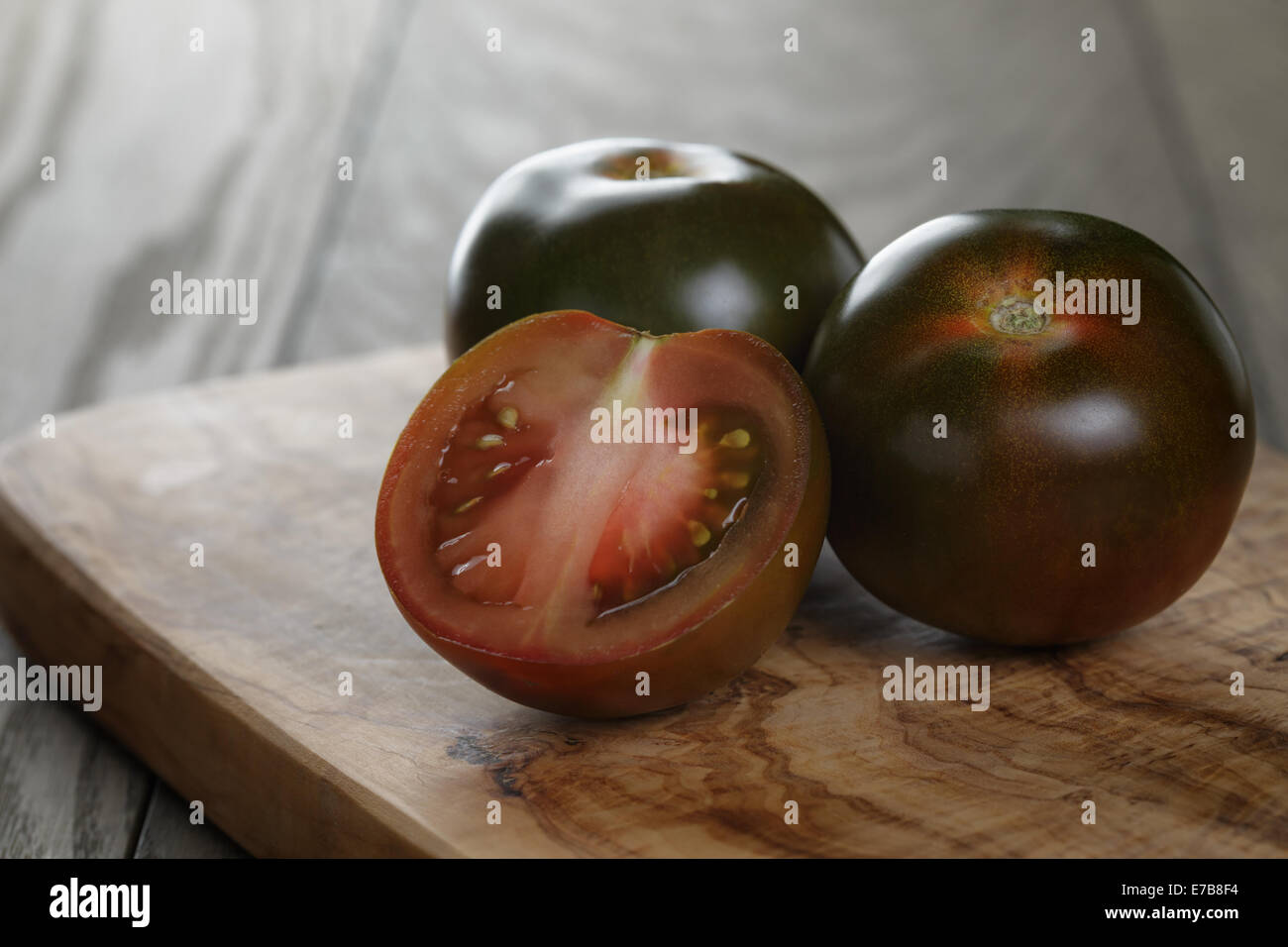 ripe kumato tomatoes on olive board, rustic style Stock Photo Alamy