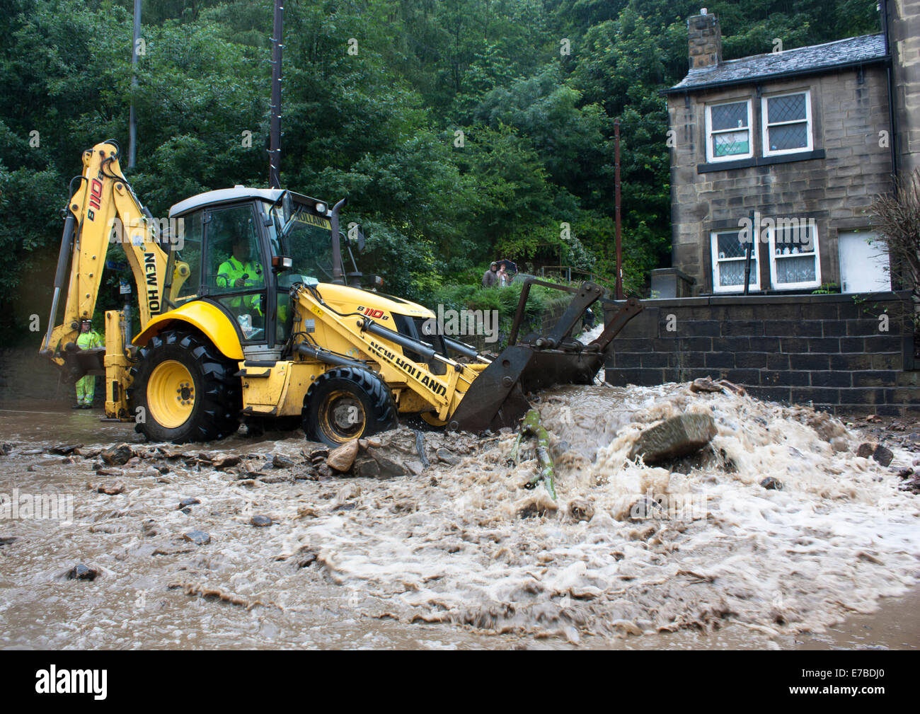 Digger clearing flood debris from a road in Hebden Bridge, West Yorkshire, UK Stock Photo