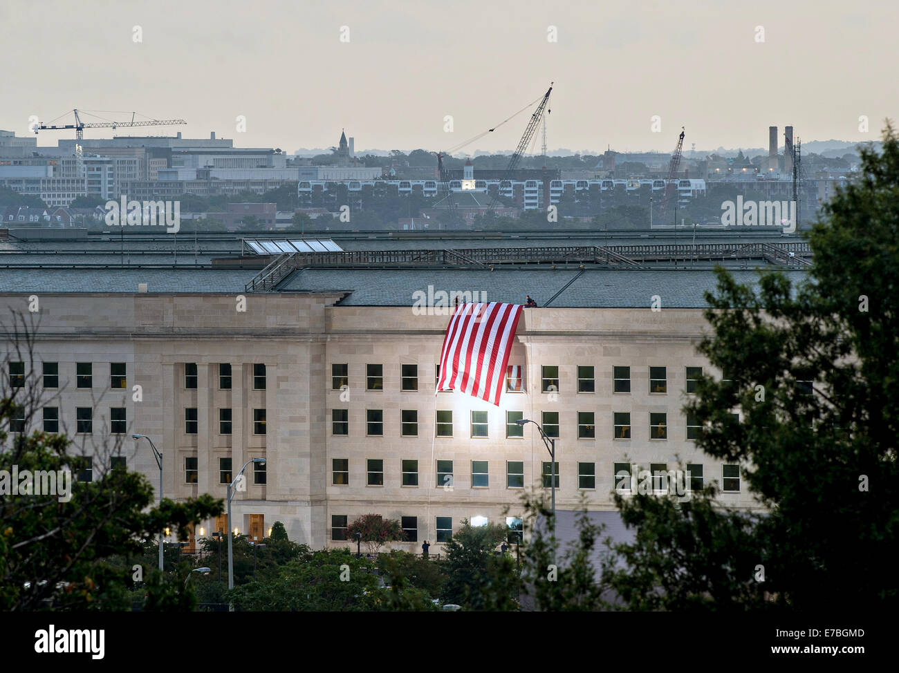 An American flag is unfurled over the side of the Pentagon at sunrise on the anniversary of the 9/11 terrorist attacks at the Pentagon September 11, 2014 in Arlington, Virginia. Stock Photo