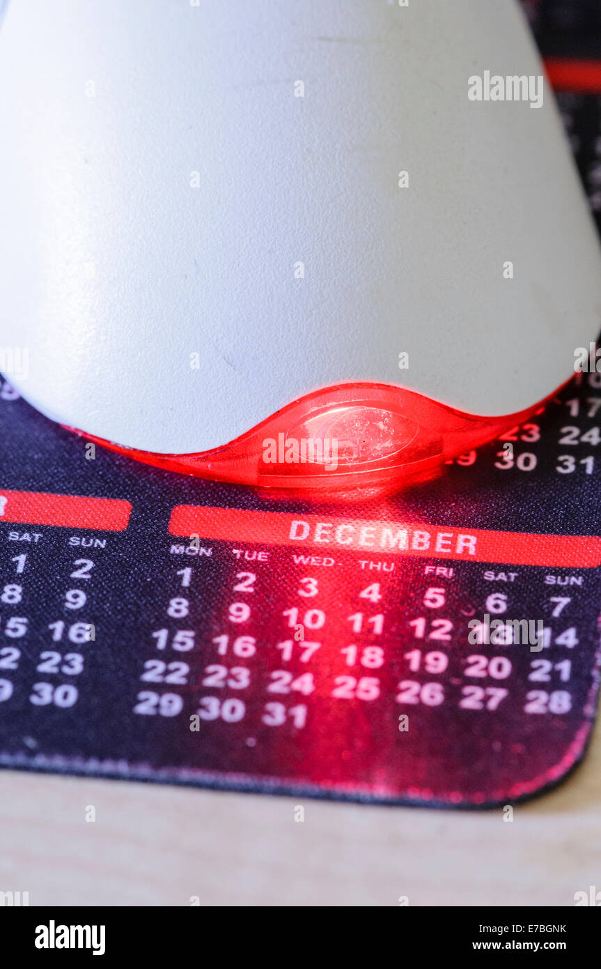 A computer mouse on a calendar mouse pad illuminating the month of December, particularly Christmas Day Stock Photo