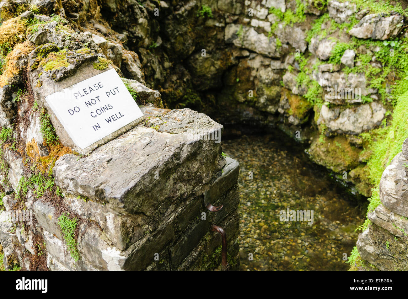 Sign asking pilgrims not to throw coins into a holy well Stock Photo