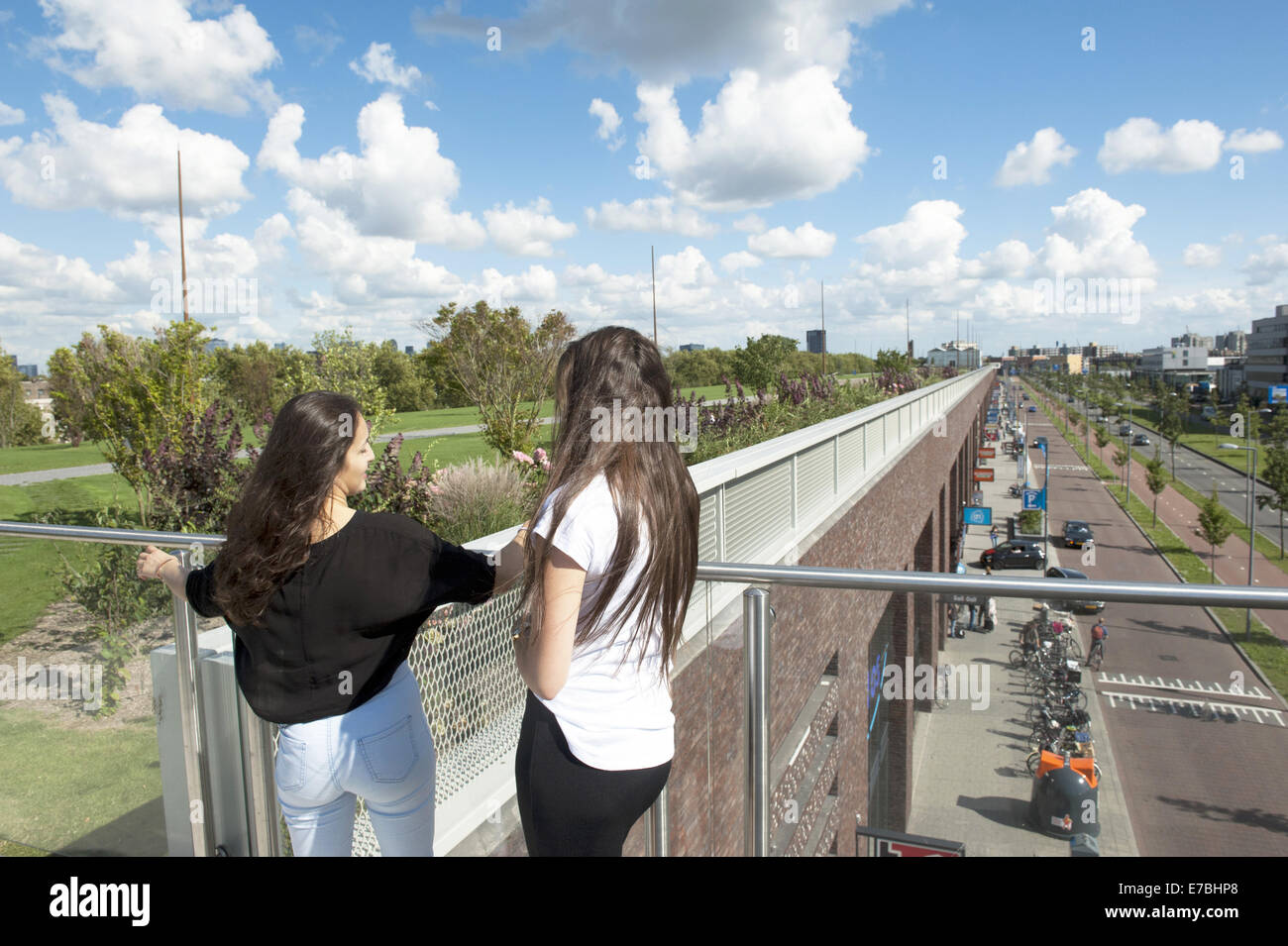 Aug. 13, 2014 - Rotterdam, South Holland, The Netherlands, Holland - A girl is standing on the roof of a commercial building. 9 metres below her is a huge shopping area. ..In Rotterdam is the largest public park on a commercial building in Europe. On 9 meters high, on top Bigshops at Marconi Plaza, is a green park with three themed gardens..The park is measuring eight acres and provides views over the city and harbor. It is 800 meters long, 80 meters wide and 9 meters high. Below the park is 25,000 m2 of retail space.It is not just a shopping area and a place where you can recreate, the same t Stock Photo