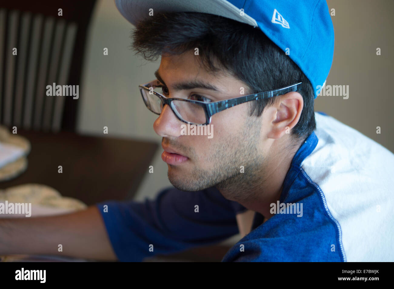 Man looking at computer wearing baseball cap Stock Photo - Alamy