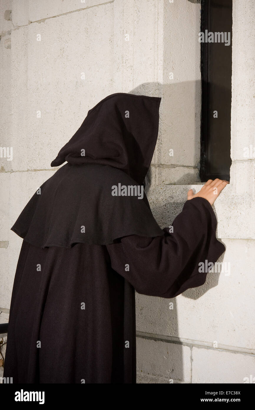 Halloween scene of a black hooded monk at a chapel window Stock Photo
