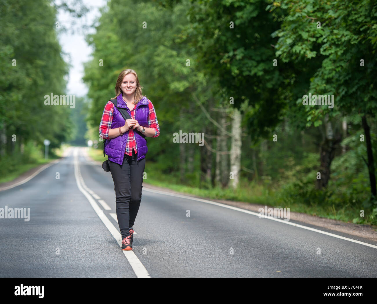 Beautiful girl with backpack walking on the road Stock Photo - Alamy