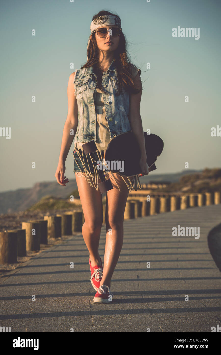 Beautiful skate girl walking while holding a skateboard Stock Photo Alamy