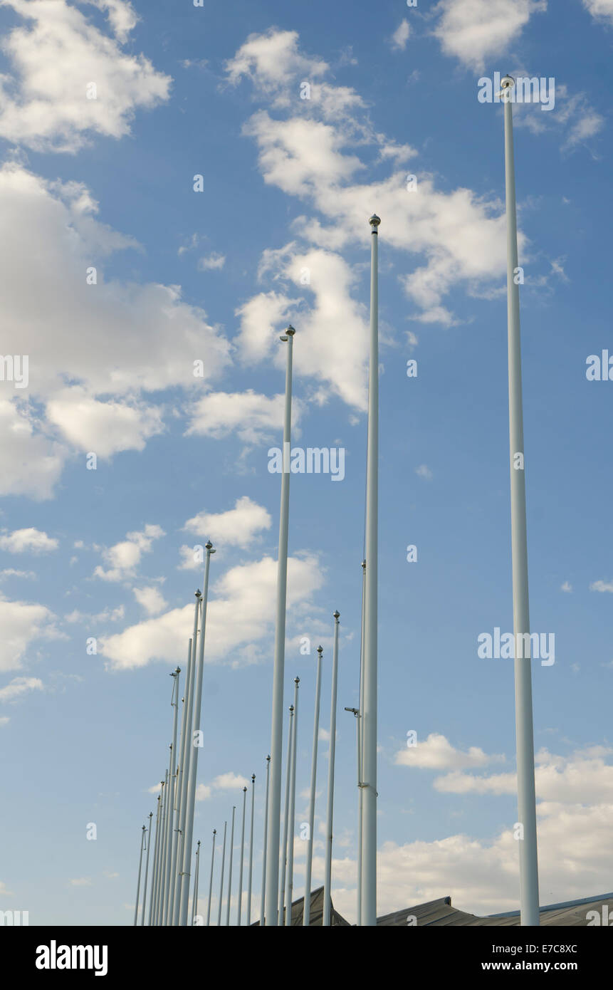 Flagpoles without flags attached against a blue sky with clouds. Stock Photo