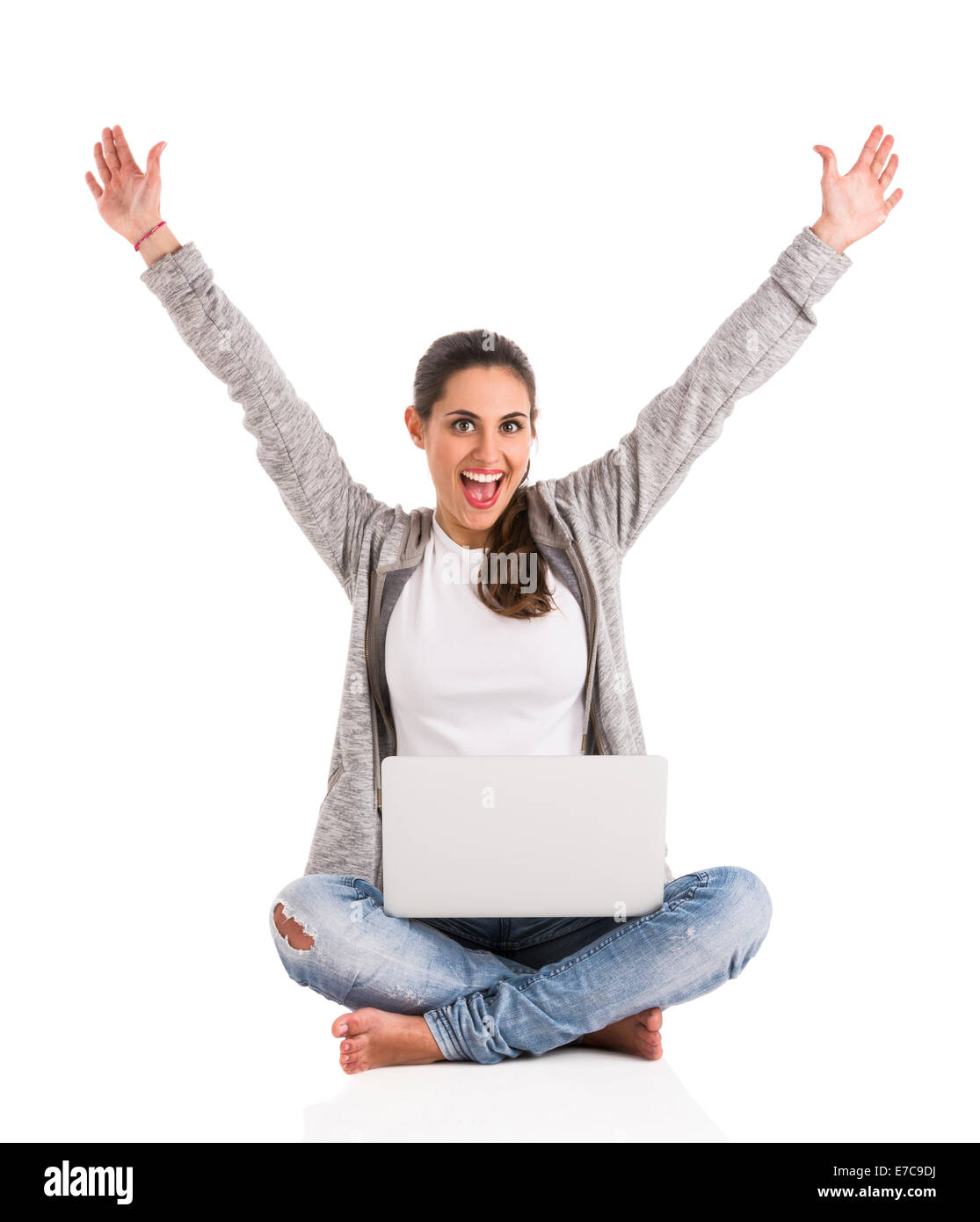 Beautiful happy woman with arms up sitting with crossed legs and working with a laptop Stock Photo