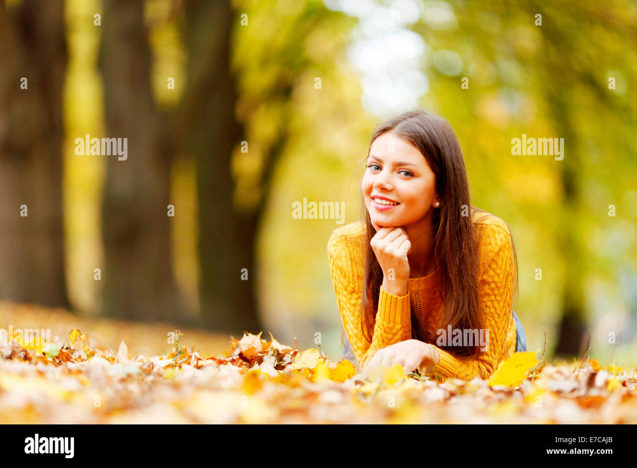 Young cute woman laying on dry leaves in autumn park Stock Photo - Alamy