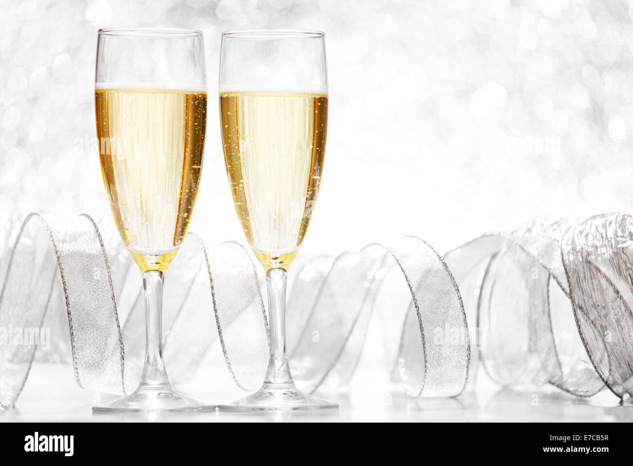 Glasses of champagne and silver ribbons on glitter background Stock