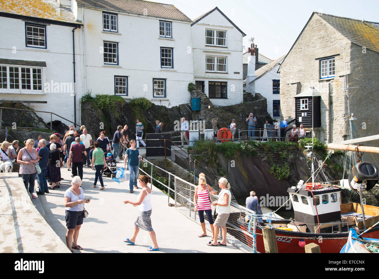 Holiday makers enjoying the sunshine on the quayside in the fishing village of Polperro, Cornwall, England Stock Photo