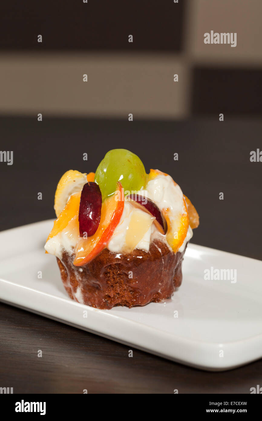 fruit cake with grapes and an orange on a white plate Stock Photo