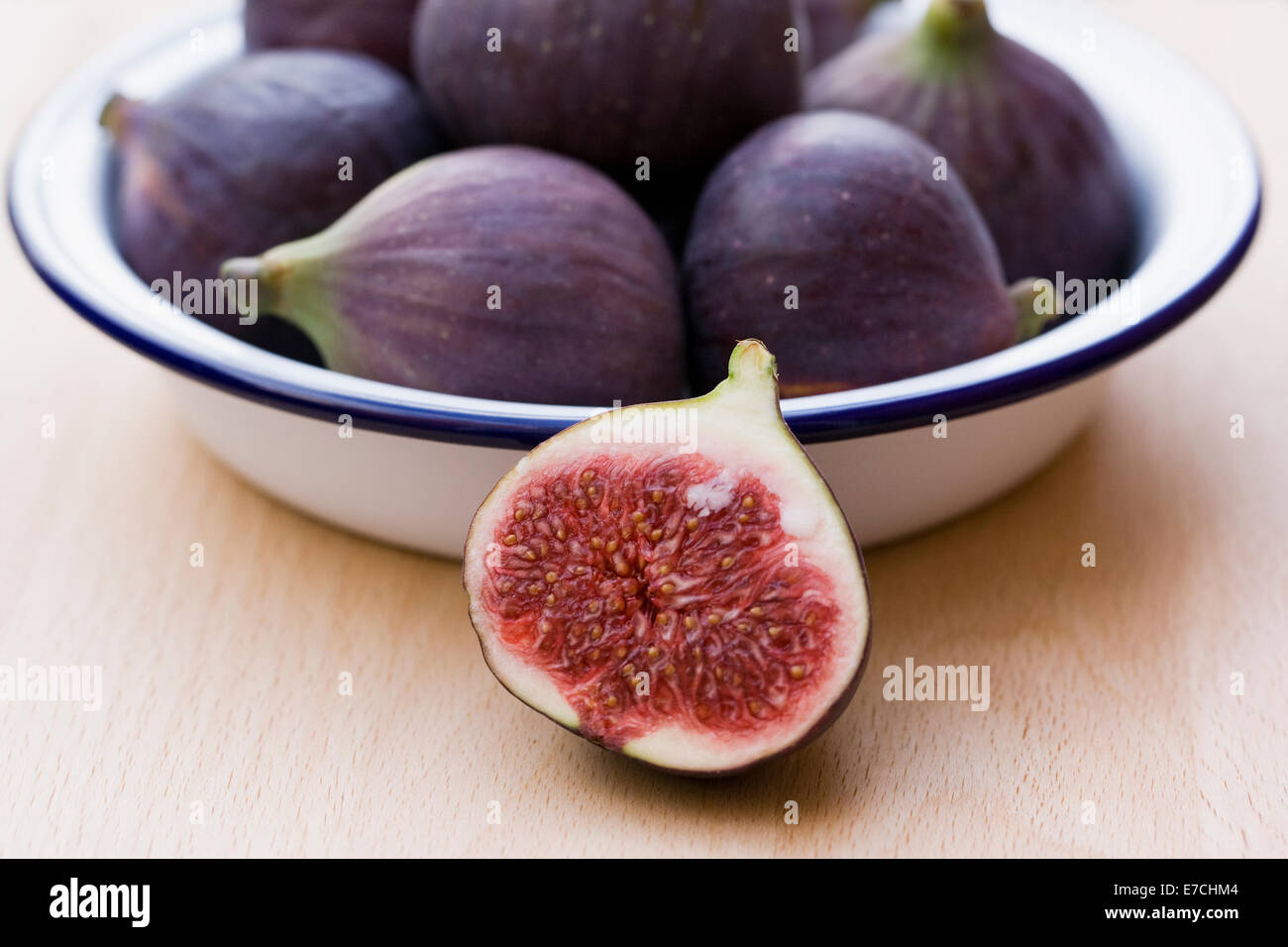 Ficus carica. Figs in an enamel dish on a wooden board. Stock Photo
