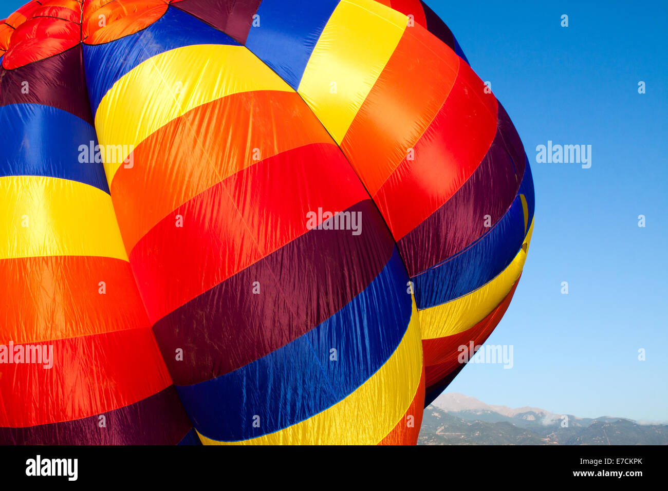 A colorful hot-air balloon being inflated with Pikes Peak in the distance Stock Photo