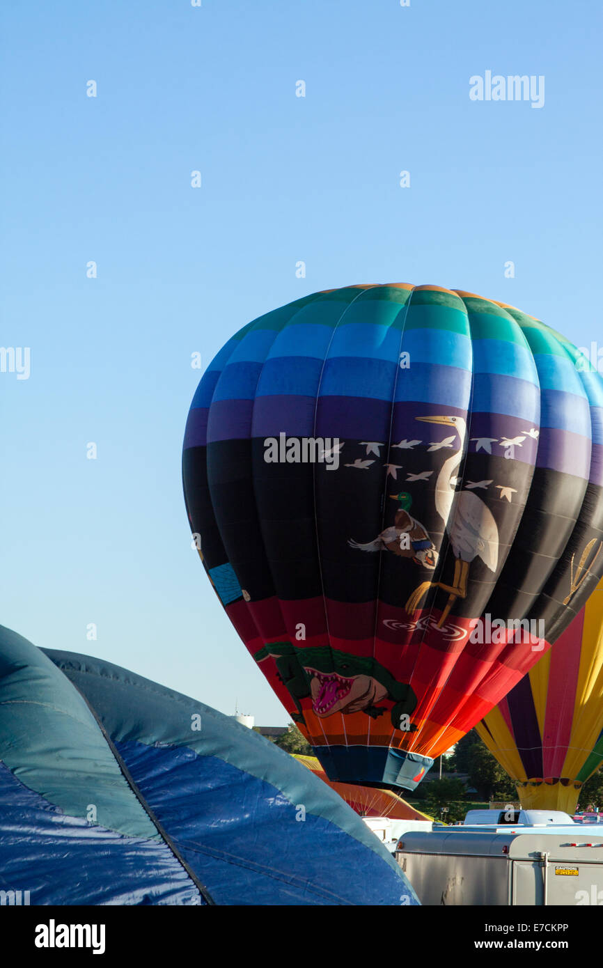Colorful hot air balloons are readied for launch against a blue sky Stock Photo