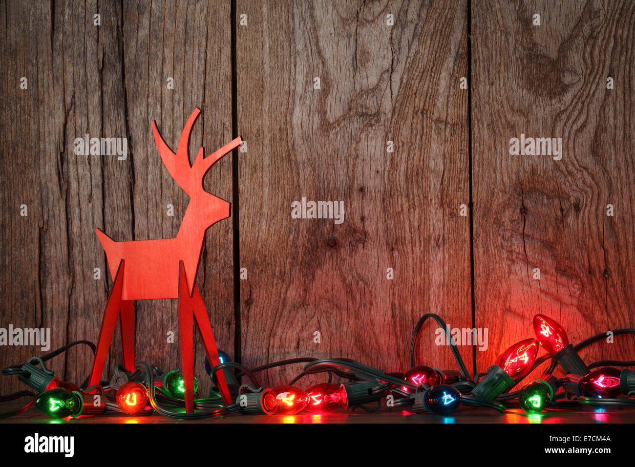 Christmas lights on wooden background with wood deer Stock Photo