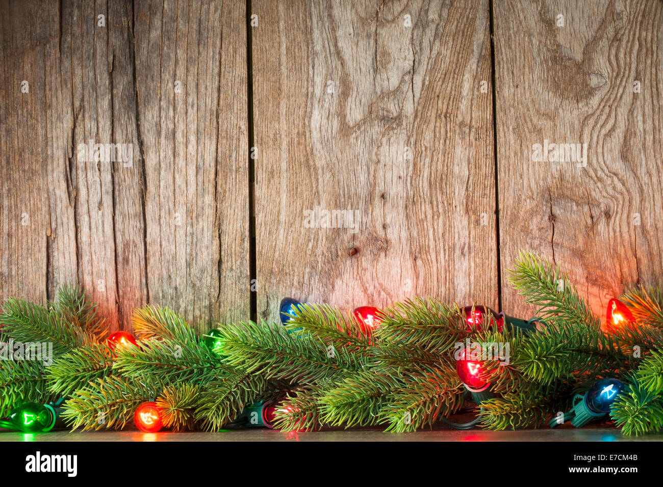 Christmas tree branch with lights on grunge wood background Stock Photo