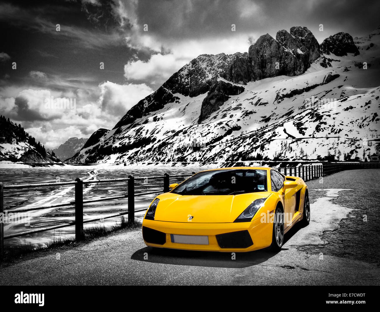 Italian supercar next to Lago di Fedaia lake surrounded by the snow and ice capped Dolomites mountains in Italy. Stock Photo