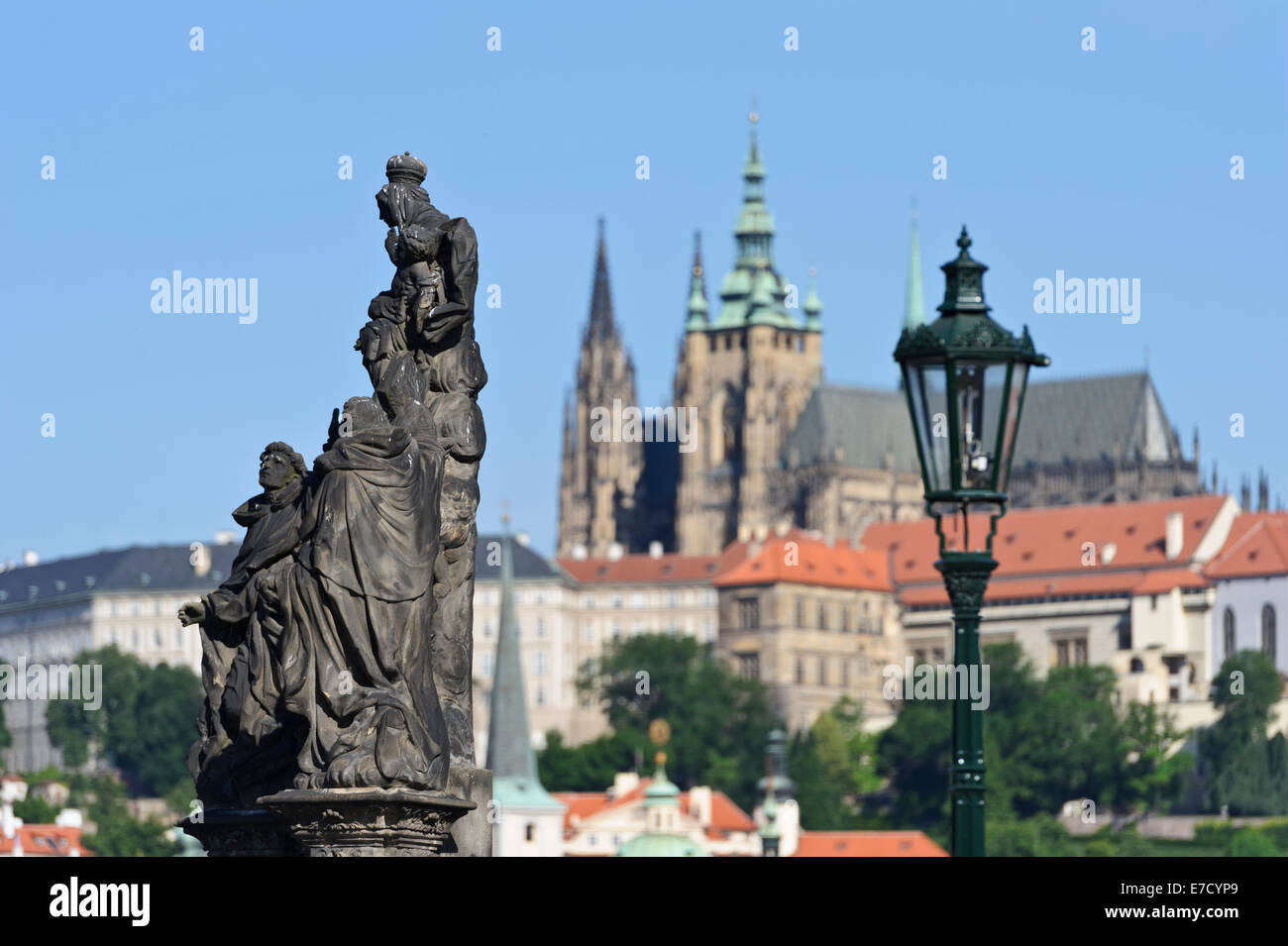 Religious statues on Charles bridge with St Vitus cathedral in the