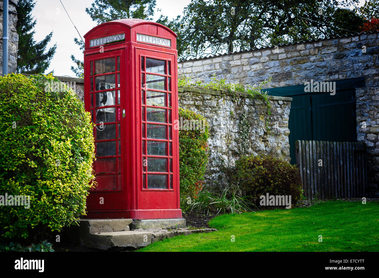 A traditional retro vintage red British UK telephone box phone booth on the side of a road in Nunnington, North Yorkshire Stock Photo