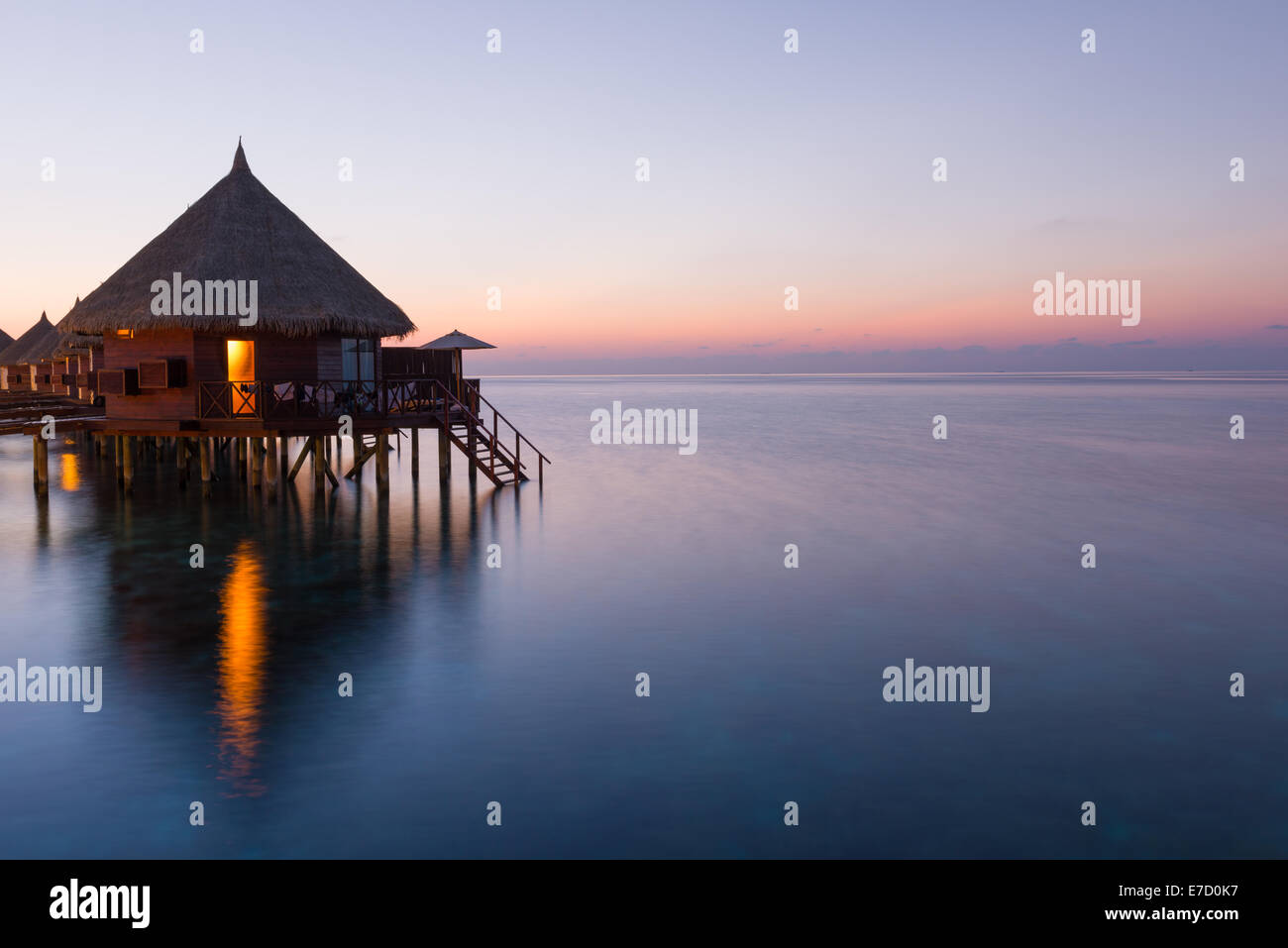 Panorama of tropical island resort with over-water bungalows at night. Maldives. Ari Atoll.  Scenic sunset over the Ocean. Stock Photo