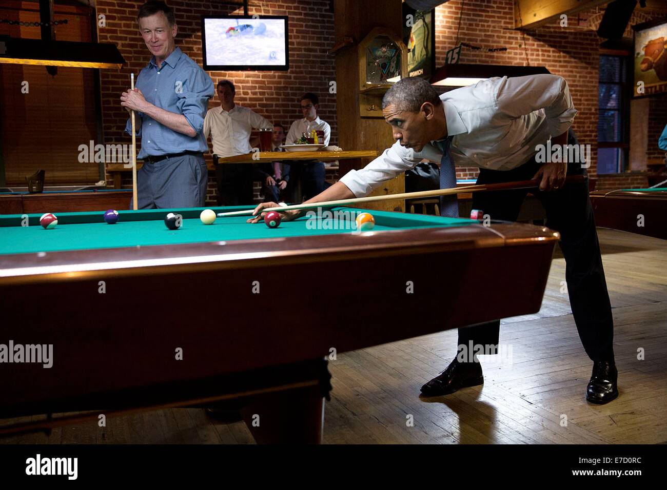 US President Barack Obama whistles along to the music as he shoots pool with Gov. John Hickenlooper July 8, 2014 in in Denver, Colorado. Stock Photo