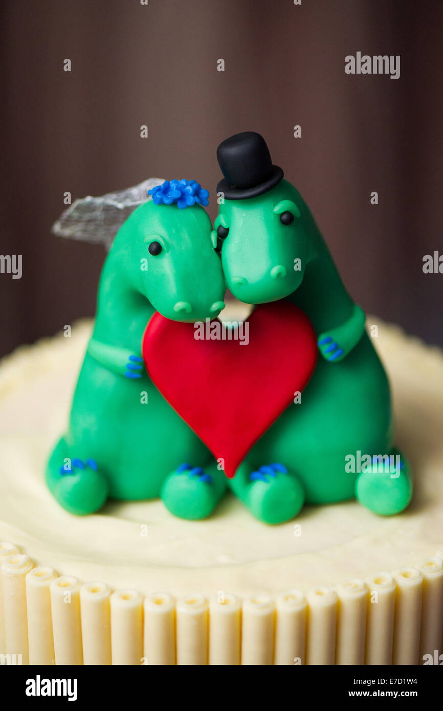 Dinosaur bride and groom cake toppers on a wedding cake Stock Photo