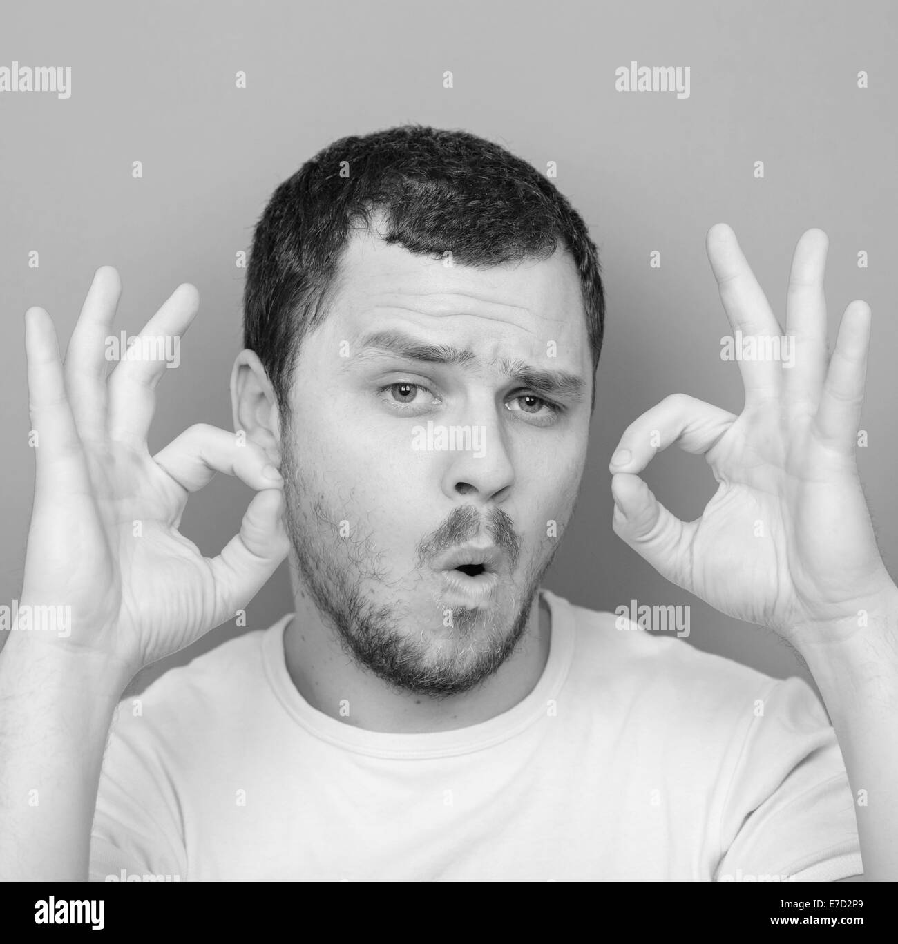 Portrait of funny man showing OK gesture with hands - Monocrome or black and white portrait Stock Photo