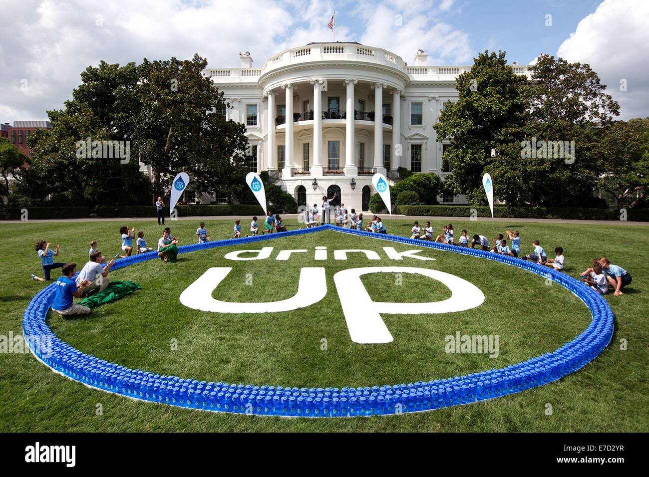 US First Lady Michelle Obama and children from local YMCA organizations and the Arlington County Department of Parks and Recreation show off the Drink Up logo during an event on the South Lawn of the White House July 22, 2014 in Washington, DC. Stock Photo