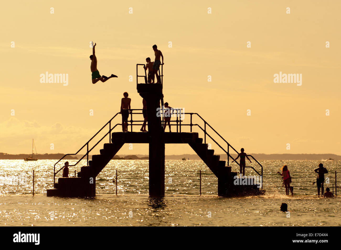 Youths diving and jumping from a sea bathing area diving platform, St