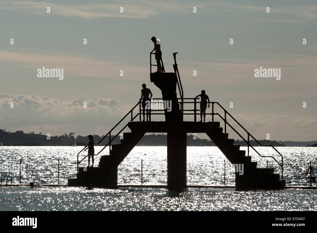 Youths diving and jumping from a sea bathing area diving platform, St