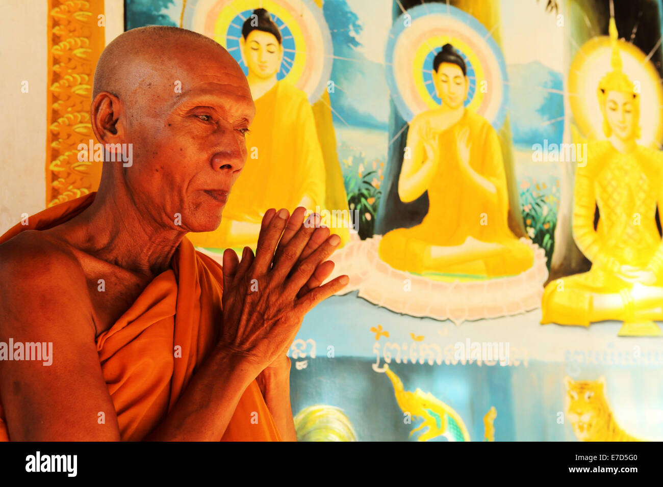 Buddhist monk praying by a colourful fresco at Angkor Wat in Siem Reap, Cambodia. Stock Photo