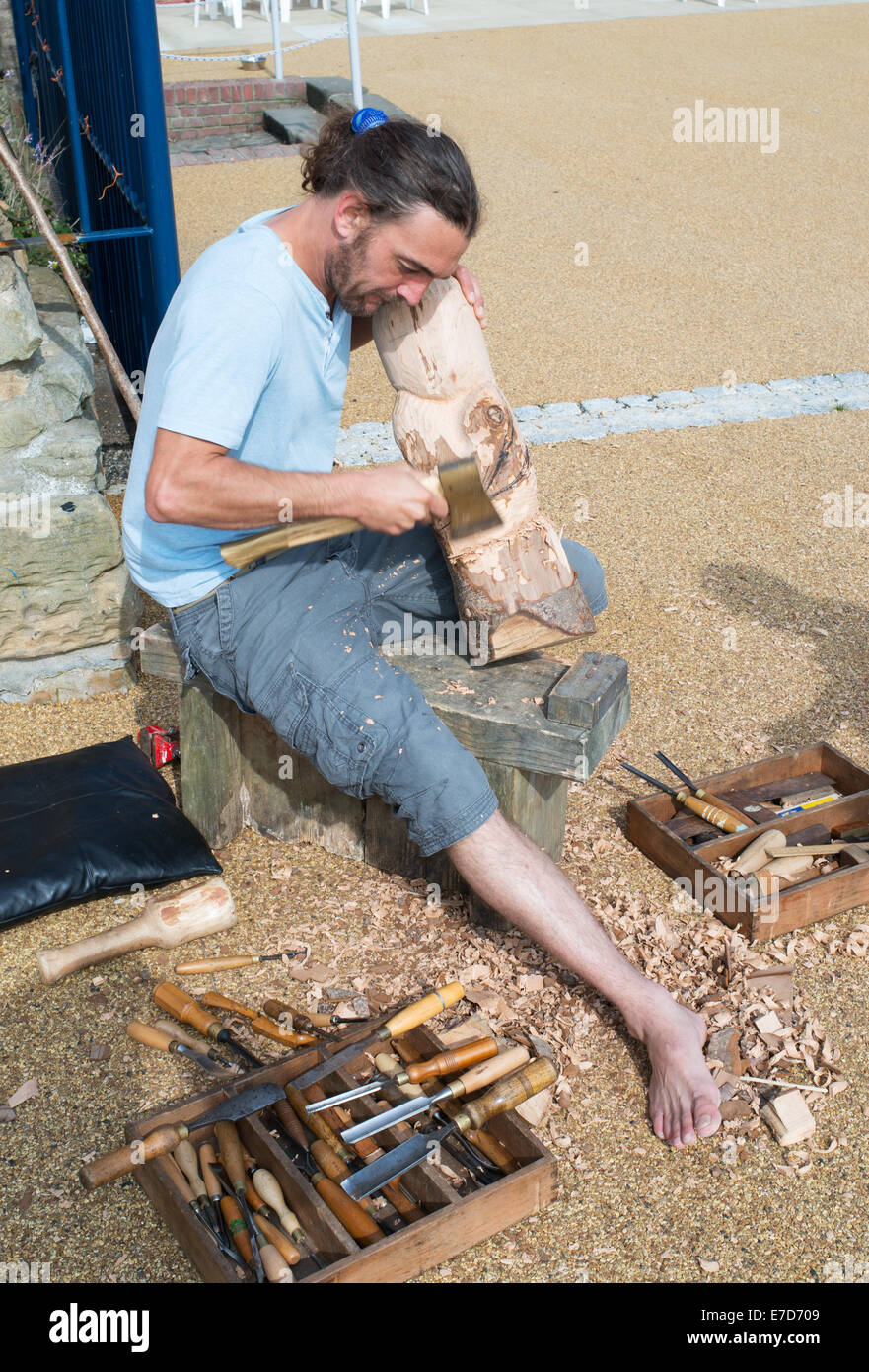 Sculptor Mark Crowley using an axe to carve a wooden Dolly or figurehead North Shields, North East, England, UK Stock Photo