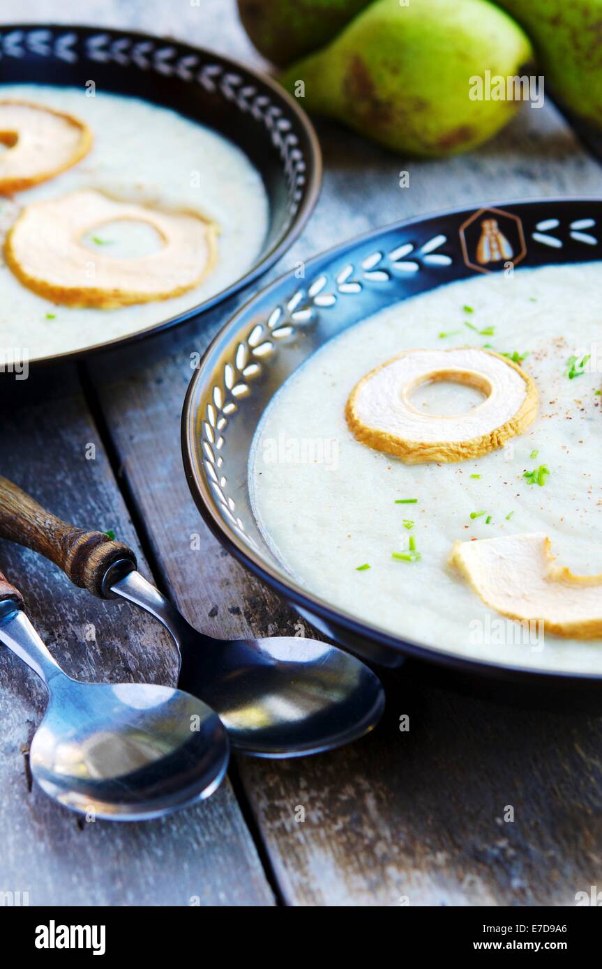 A creamy fall season soup with pears and celery root, garnished with dried apple rings. Stock Photo
