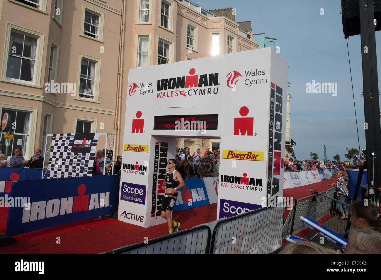 finish,line,marathon,event,Tenby, Pembrokeshire, Wales, UK. 14th Sep, 2014. British athlete Harry Springall 5th placed finisher in time of 9 hours, 52 mins, 5 secs at finishing line after running section of IRONMAN WALES in Tenby, Pembrokeshire, Wales. This triathlon involves 2.4 mile swim, 112 mile bicycle ride and 26.2 mile run. Credit:  Paul Quayle/Alamy Live News Stock Photo