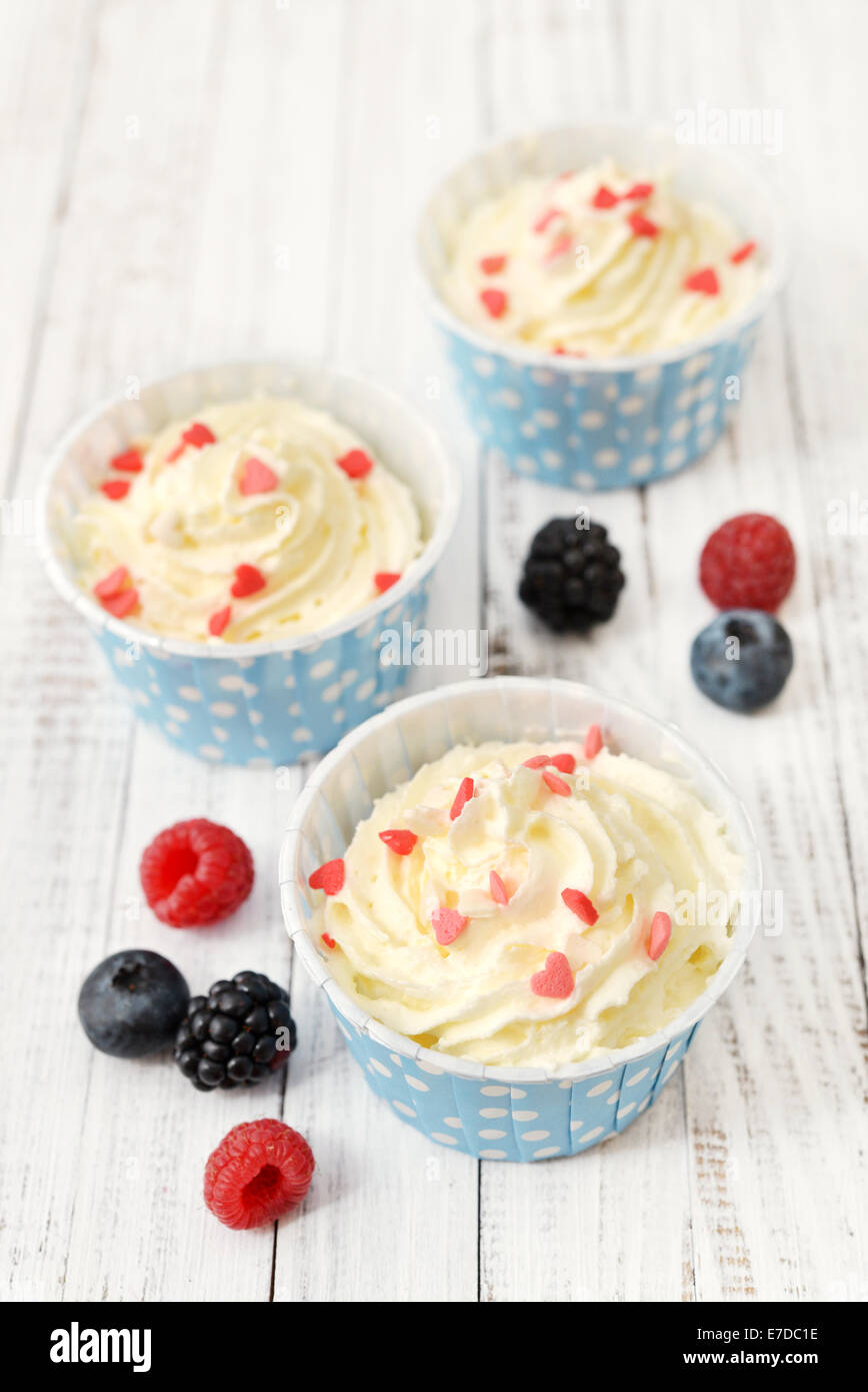 Fresh berries with frozen yogurt in paper cup on wooden background Stock Photo