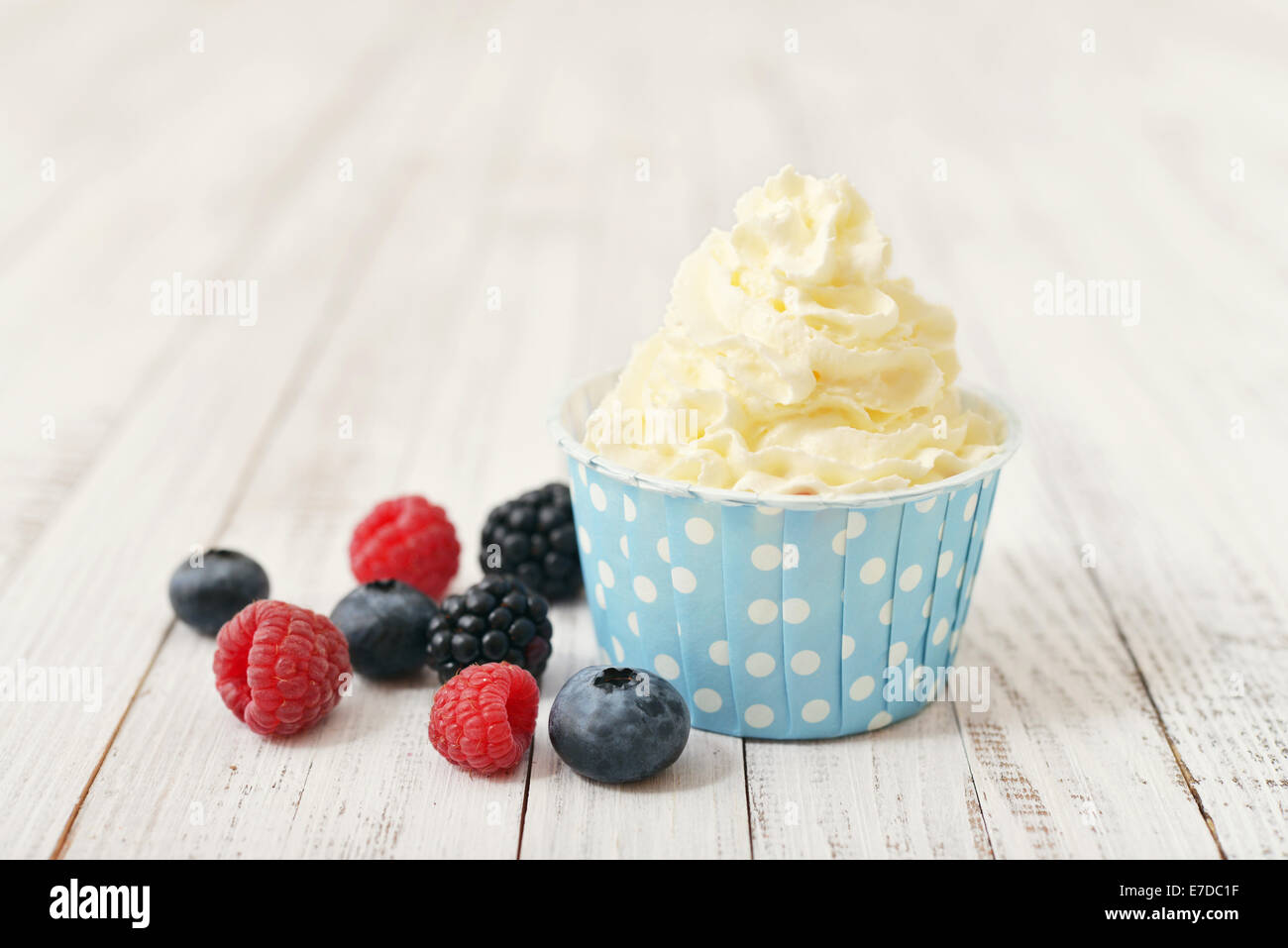 Fresh berries with frozen yogurt in paper cup on wooden background Stock Photo