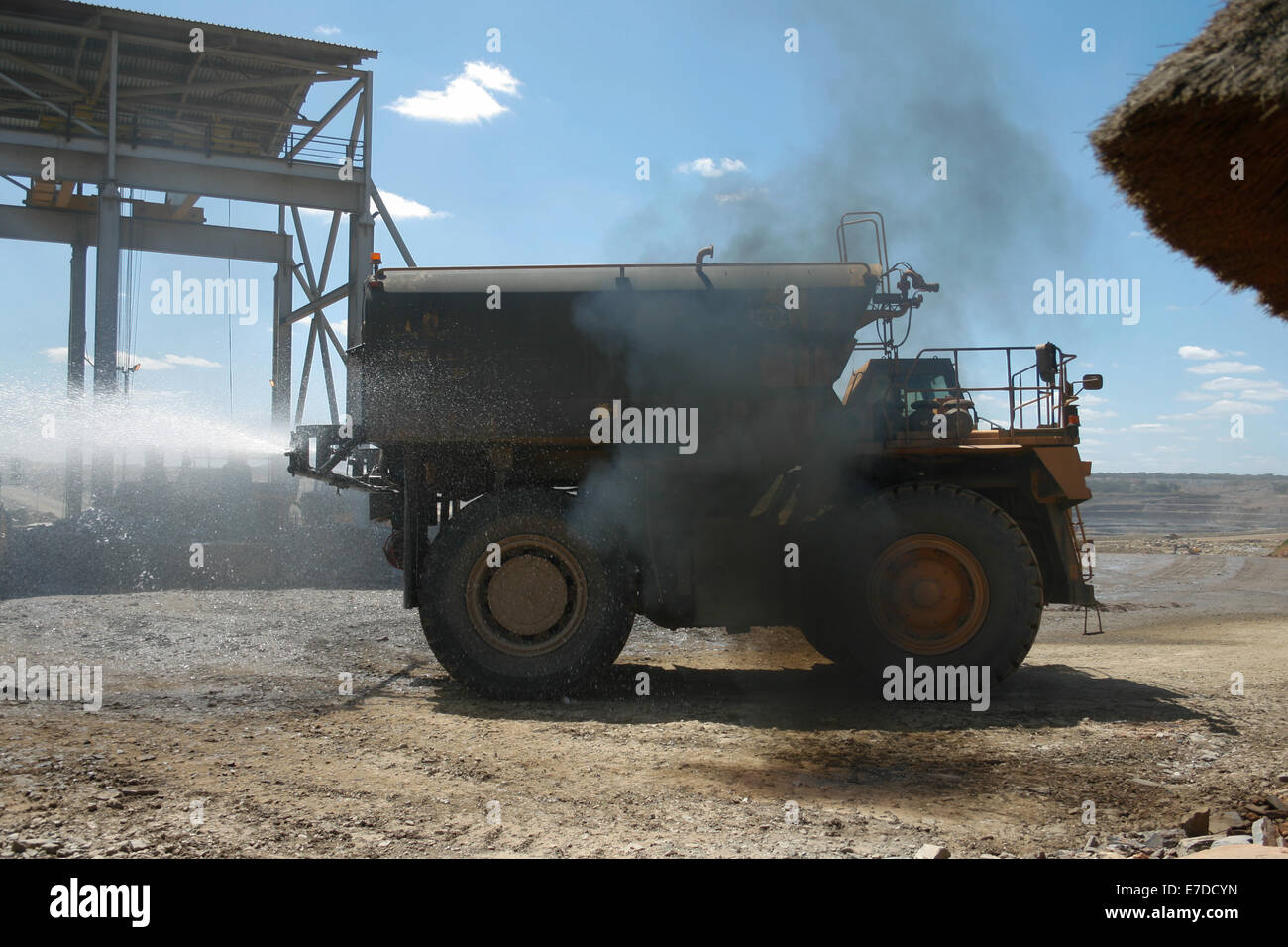 A Komatsu dust supression water truck belches smoke out in a large African open cast copper mine Stock Photo