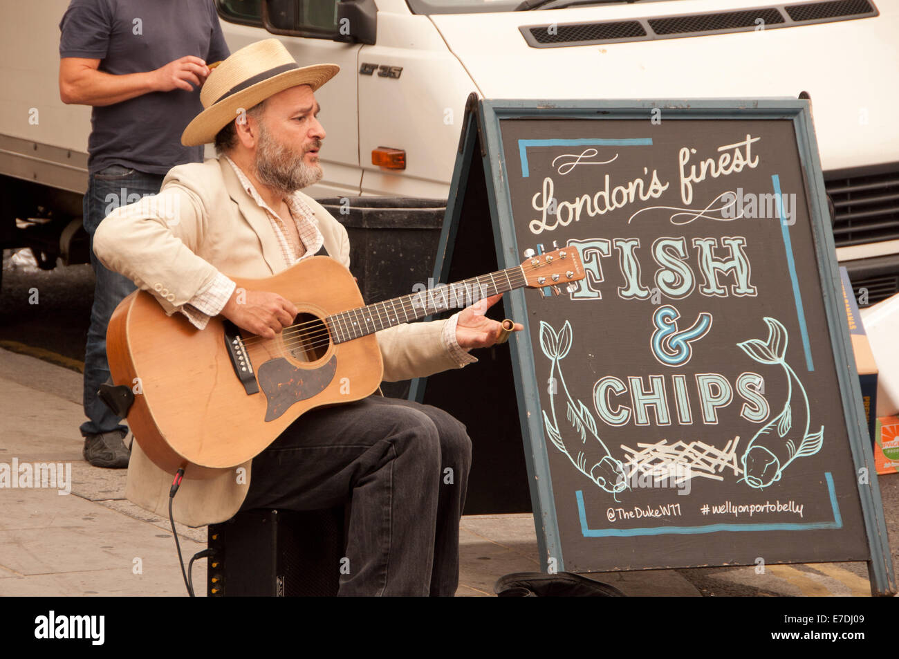 Guitar Busker on London Street with Fish & Chips Sign Stock Photo