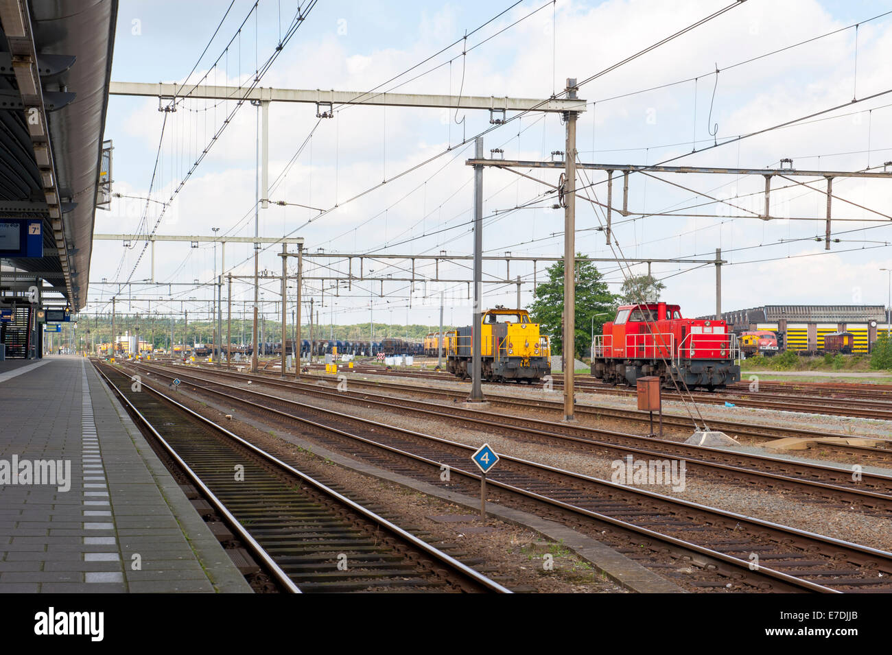 Platform with railway tracks and red and yellow cargo locomotives Stock Photo