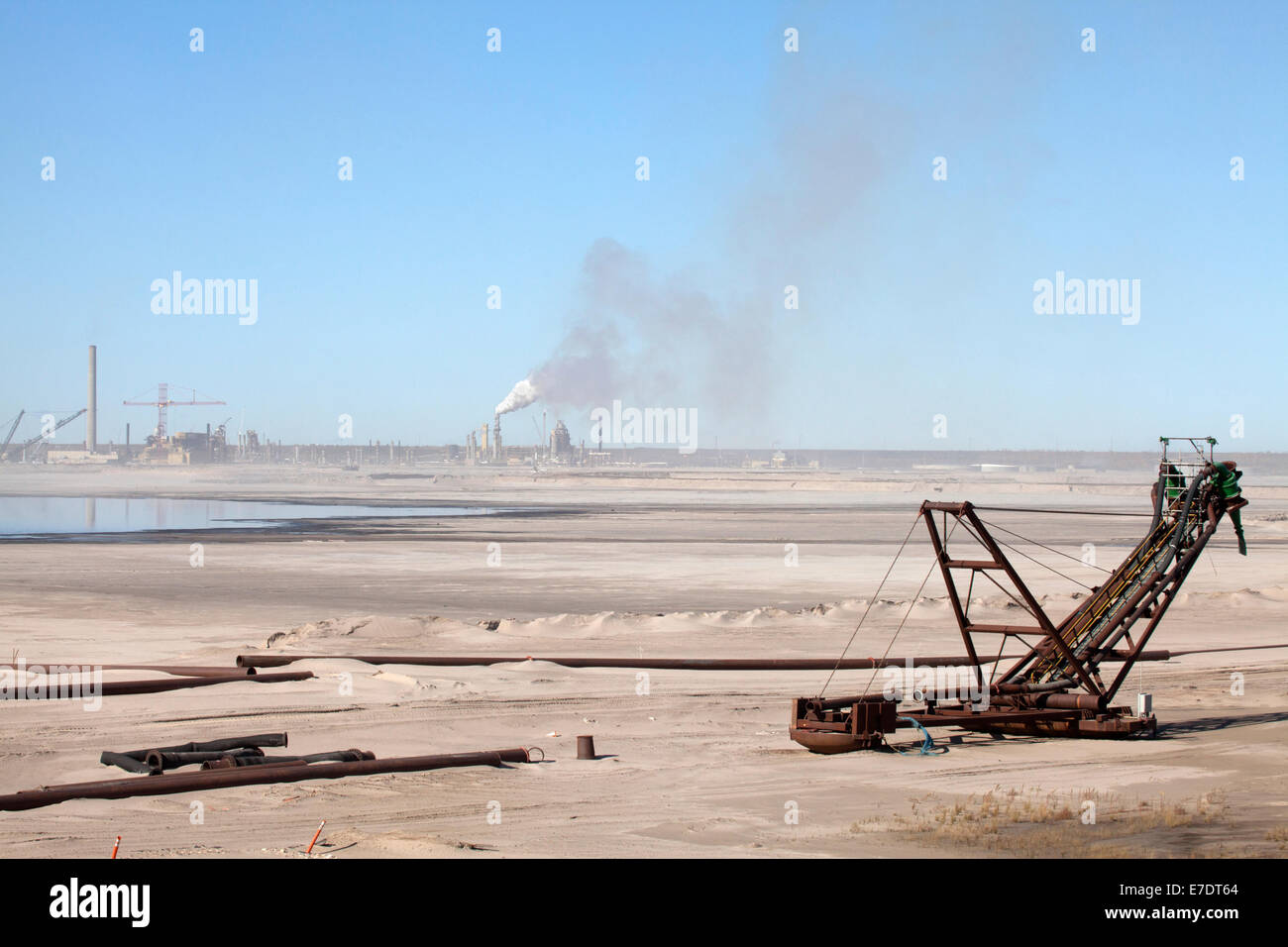 Industrial landscape with abandoned heavy machinery and distant smoke stacks at Fort McMurray, Alberta, Canada Stock Photo
