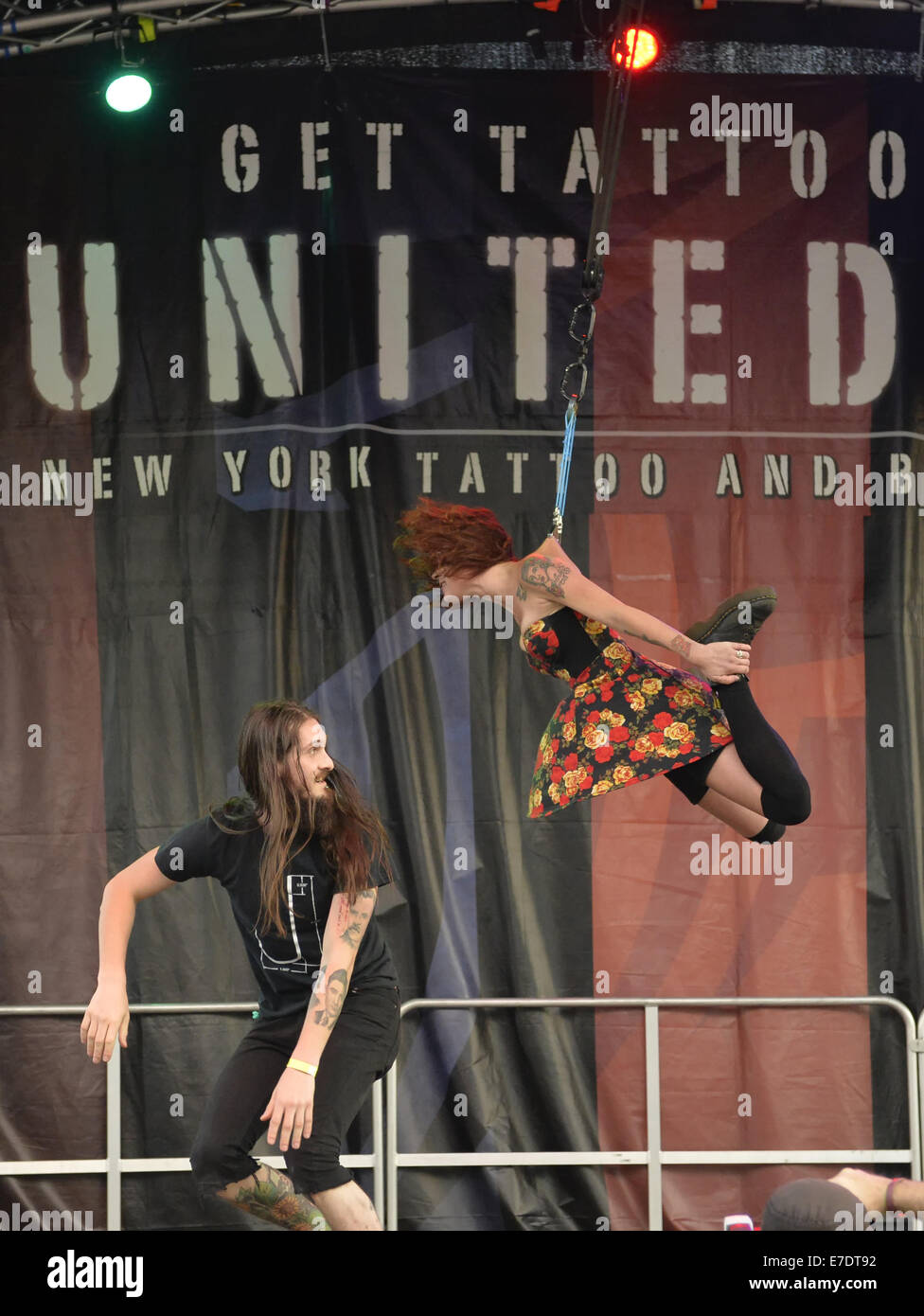 Garden City, New York, USA. 14th Sep, 2014. Young woman with tattoos is suspended from two ropes with hooks pierced through the skin of his back, at an outdoor body suspension show at the United Ink Flight 914 tattoo convention at the Cradle of Aviation museum of Long Island. Credit:  Ann Parry/ZUMA Wire/Alamy Live News Stock Photo