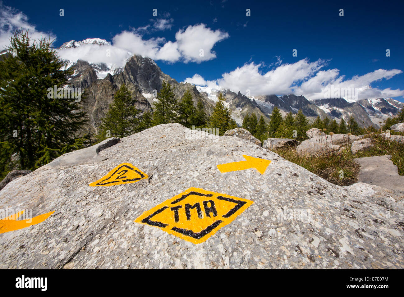 Looking towards Mont Blanc from above Val Veny, Italy, with a rock marked with the Tour du Mont Blanc long distance footpath. Stock Photo
