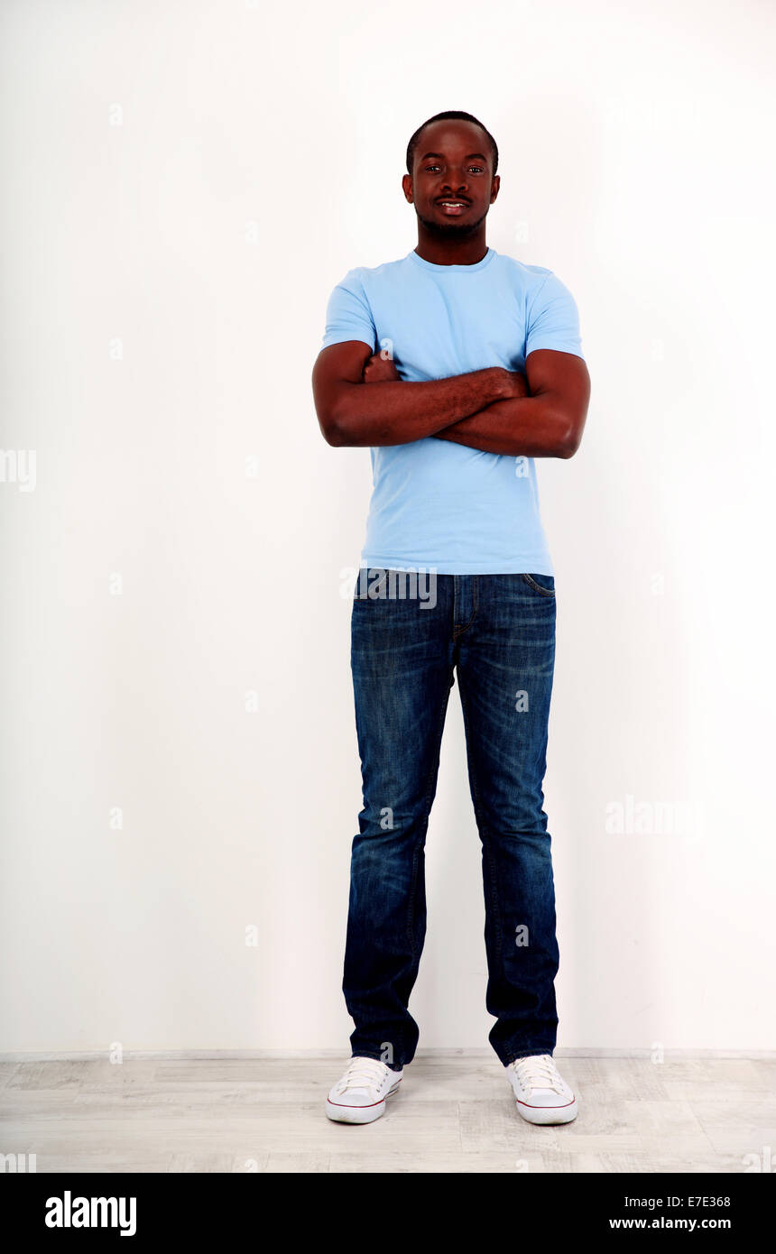 Full length portrait of a happy african man standing with arms folded ...