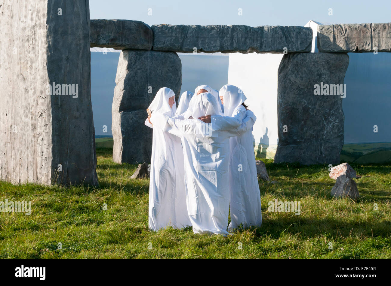 Several women with joined arms and dressed as druids in a mock build of stonehenge at the goodwood revival 2014 Stock Photo