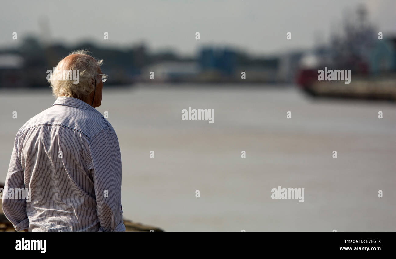 Old grey haired senior man looking across Great Yarmouth Harbour Stock Photo