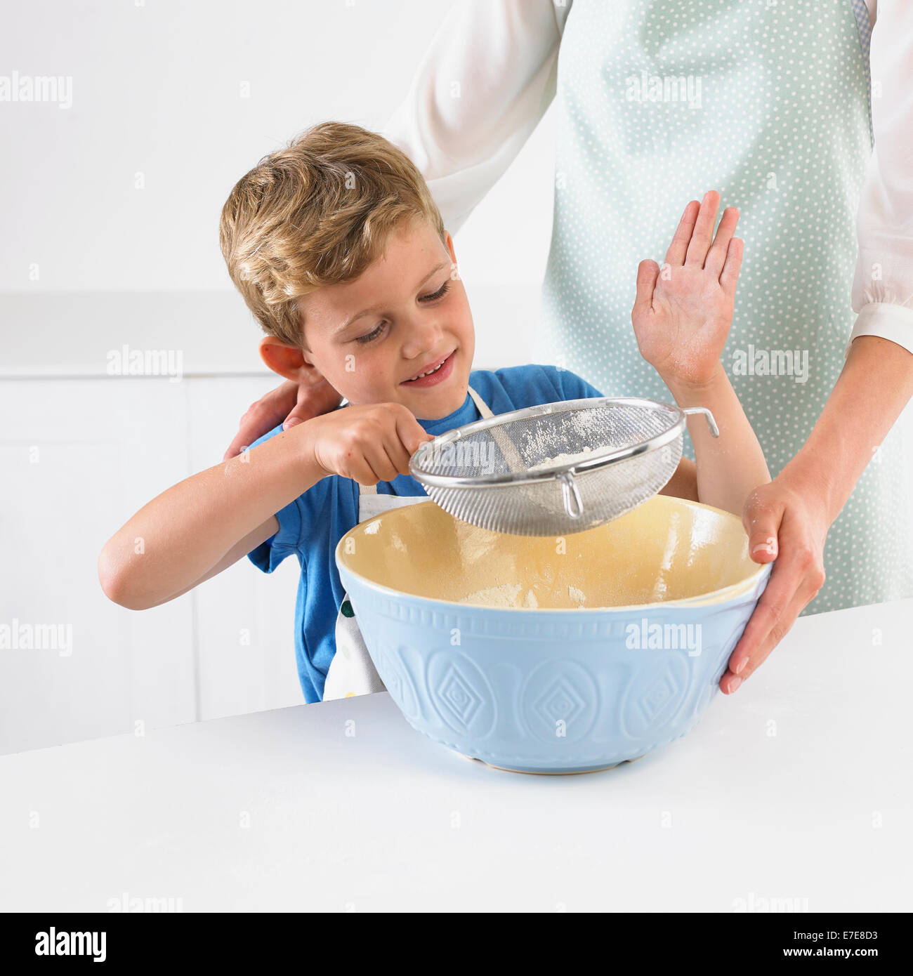 Young boy sifting flour into mixing bowl Stock Photo