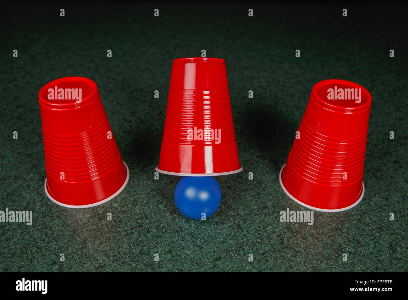 Shell Game three red cups and a blue ball on a green table arranged