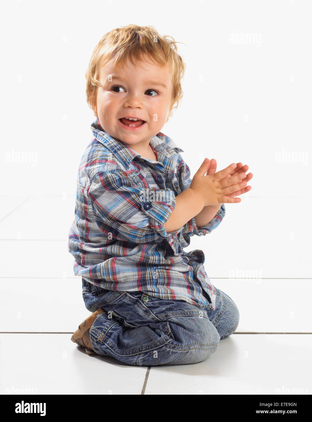 Kneeling baby boy clapping his hands Stock Photo Alamy