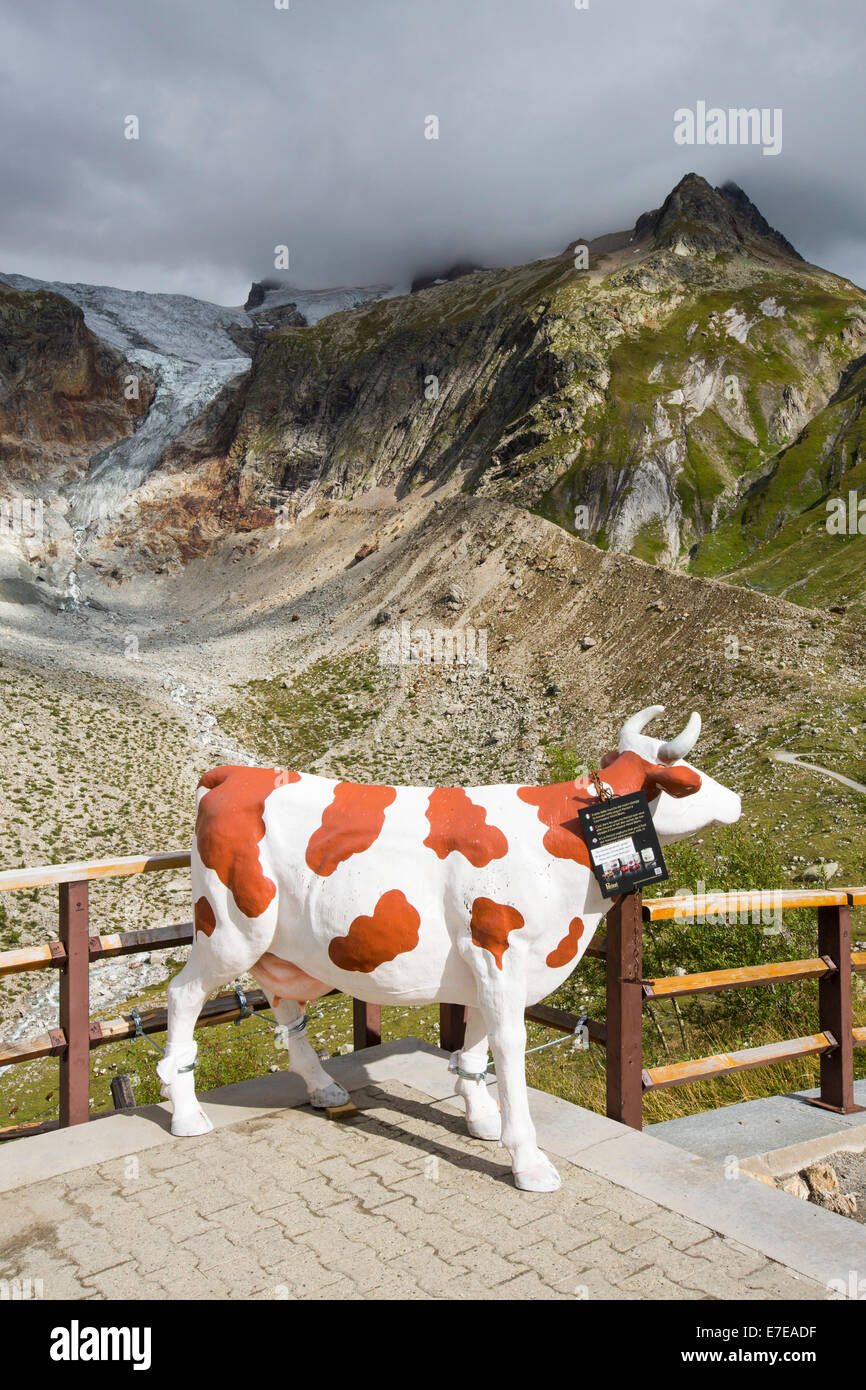 A model dairy cow infront of the rapidly receding Glacier de pre de Bar in the Mont Blanc range, Italy. Appropriate as methane emissions from cows are a driver of climate change. Stock Photo